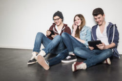 teens sitting on floor using technology