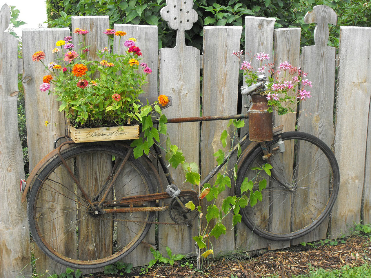 about bicycle with flowers in basket on fence